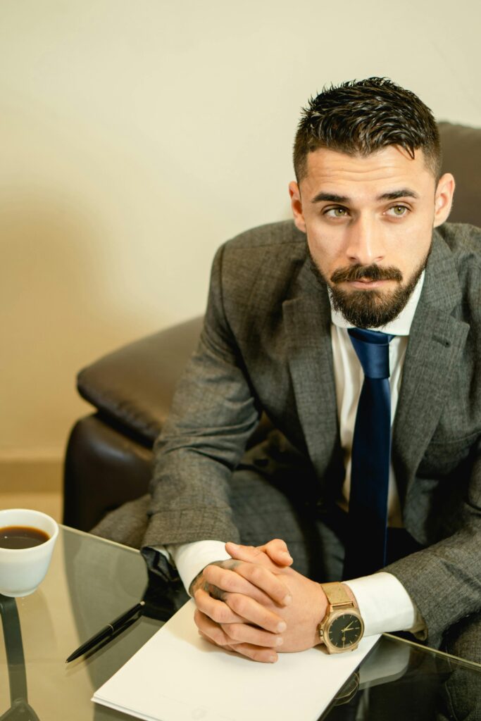 Professional portrait of a businessman in a suit sitting at a table with a coffee cup.