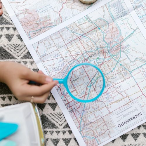 pexels-photo-8082825-8082825 A top view of a hand holding a magnifying glass over a map, emphasizing exploration.